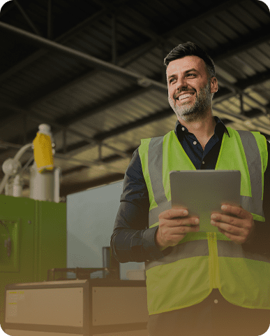 Smiling worker in safety vest with tablet.
