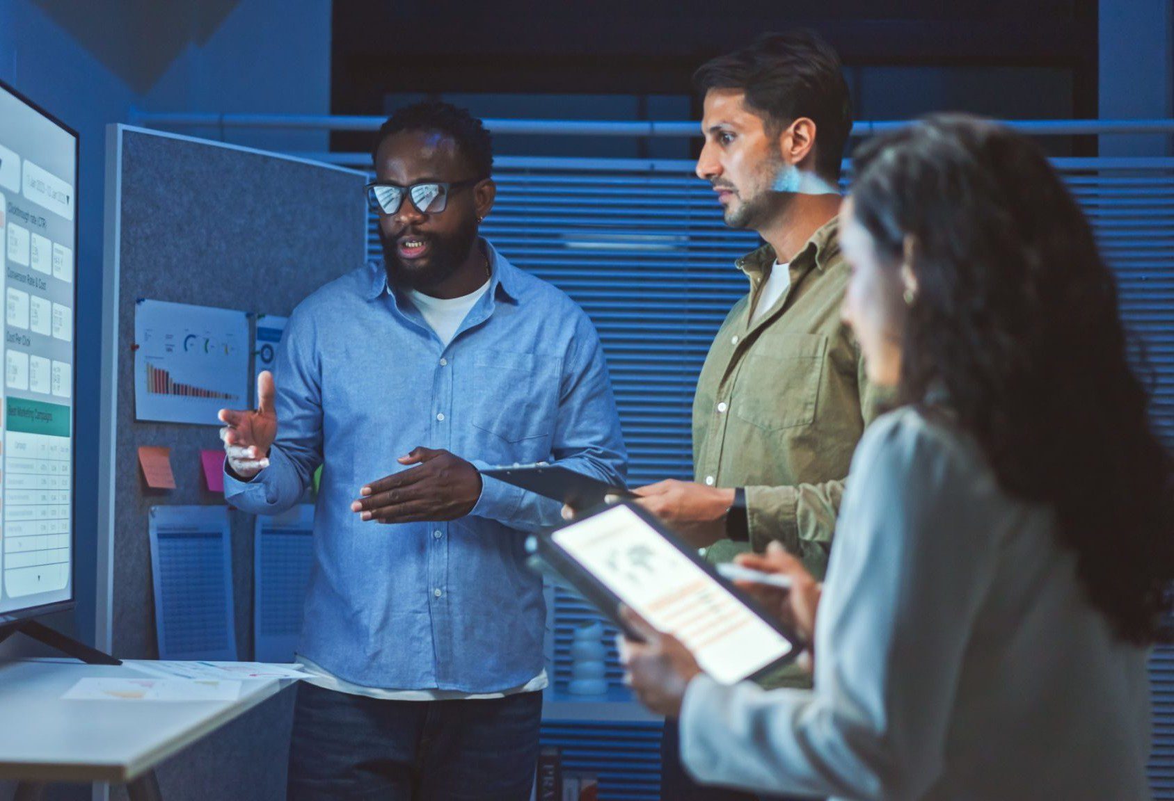 Three professionals discussing work in a modern office setting.
